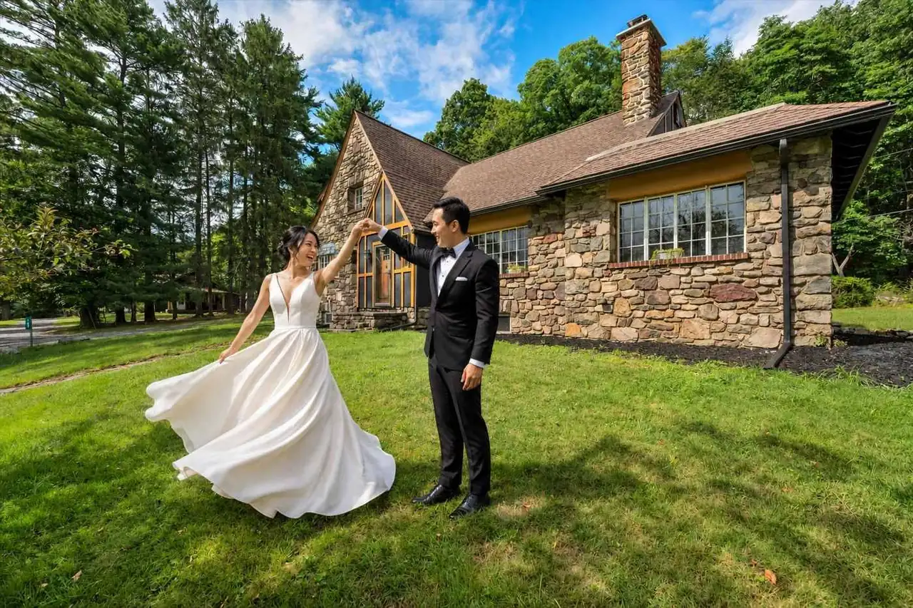 A wedding couple on the lawn beside a stone house