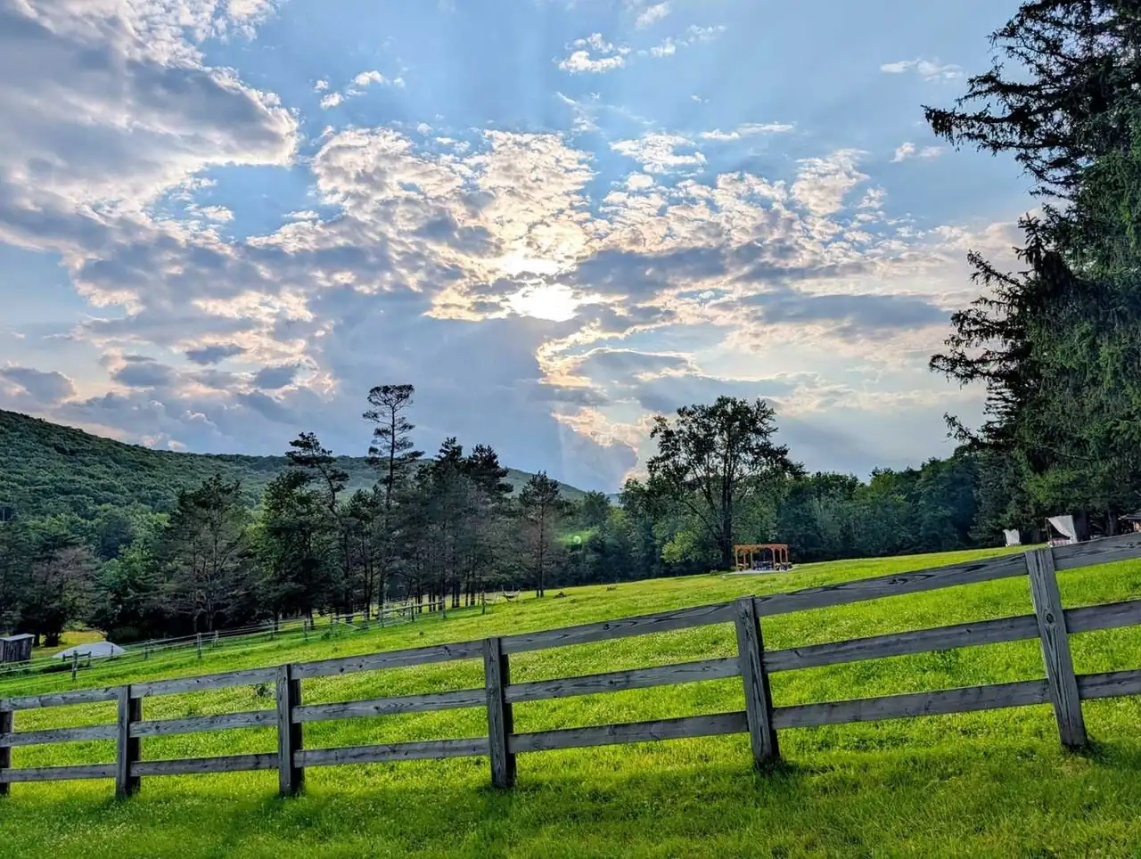 Split-rail fence and lawn below the ridge under a dramatic sky