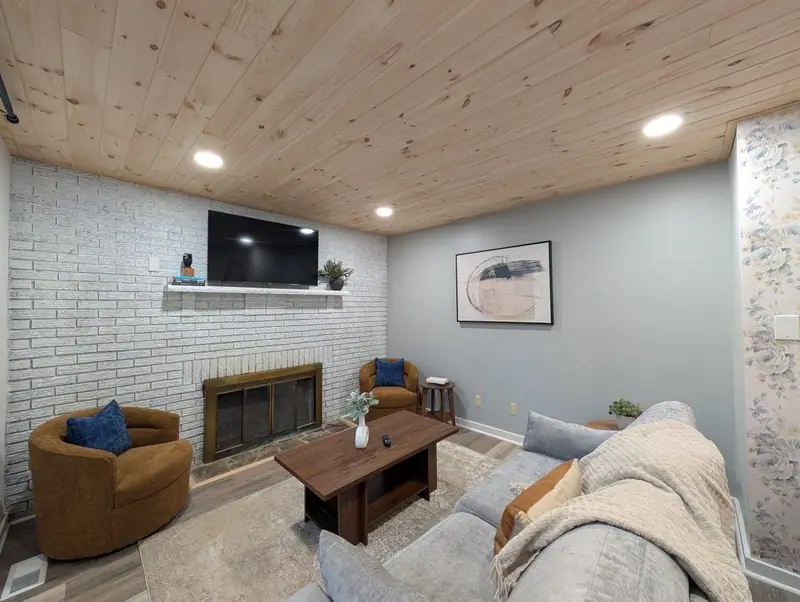 Charming white-brick fireplace as the living room's focal point, with soft throws and space for everyone.
