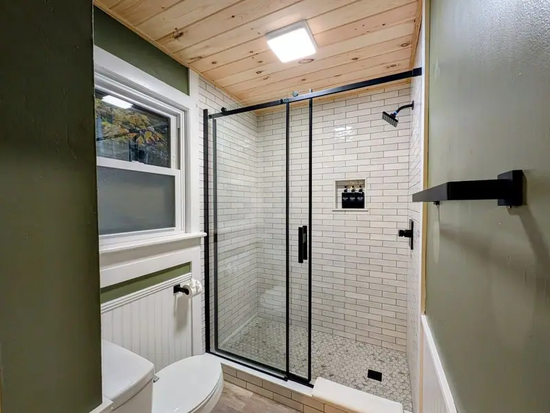 Step into the glass walk-in shower, finished in clean white subway tile.