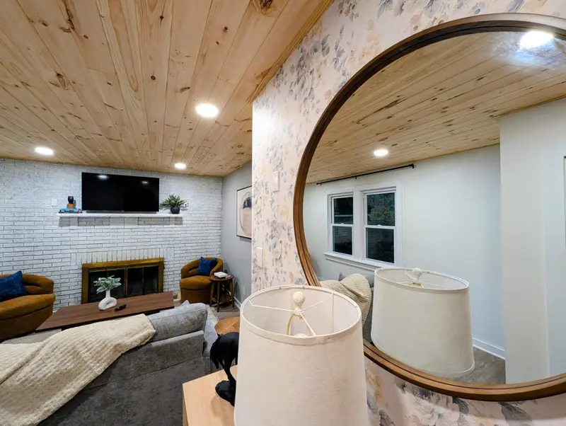 Caught in the round mirror: warm wood ceilings, soft light and a living room made for slowing down.