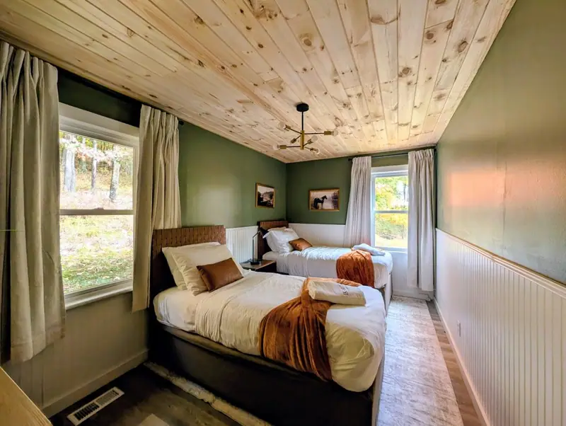 Golden fall light pours through two windows onto the twin beds of Bedroom 2.
