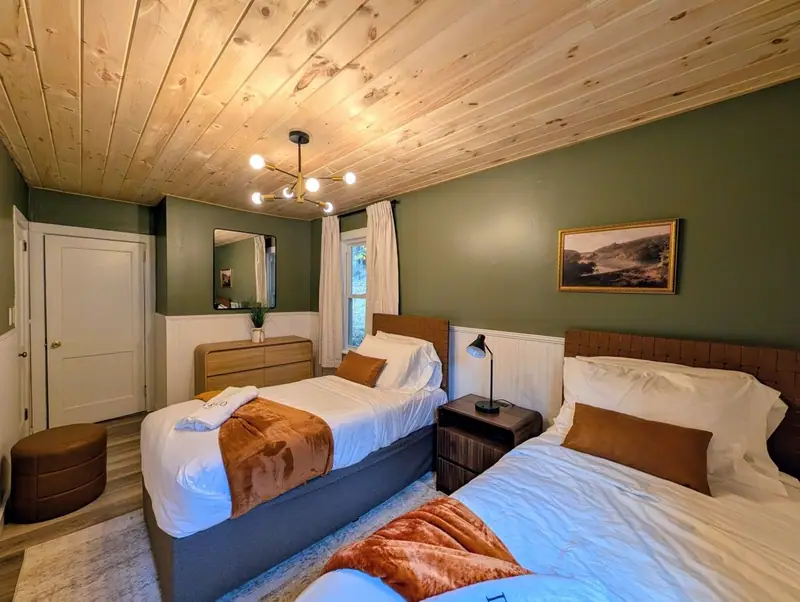 Beneath a sweeping landscape painting, side-by-side twin beds make every night a sibling sleepover.